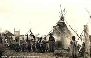 A group of children near a teepee with a church in the background, [Alberta].