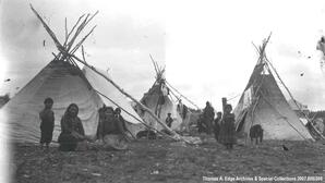 Indian village with numerous people, three teepees and one dog, [Alberta].