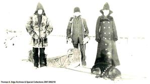 One man and two boys with a sled, Hay River, Northwest Territories. Note on the back reads: ""Anglican Missionaries going down Hay River"".