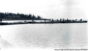 Three or more scows landed on a small island on a river. There are also a tent and two horses on the island, [Alberta].