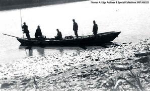 One scow on edge of shore with five men in it. One man with long pole is landing the scow, [Alberta].