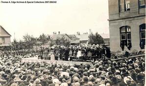 An event or ceremony taking place outside on a stage with a large crowd gathered around, Edmonton