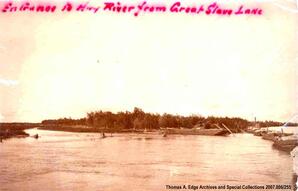 Land surrounded by water with numerous boats both landed and in the water, Northwest Territories. Note on the front reads: ""Entrance to Hay River from Great Slave Lake"".