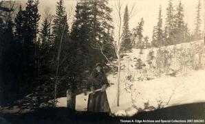 One Indian woman in a forest with an axe, Fort Chippewyan. Note on the back reads : "Indian woman cutting wood at Chippewyan 25".