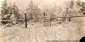 A field with a fence with the gate open. The ground is covered in snow, [Alberta]. Note on the back reads: "RCMP gate".