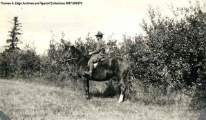 Portrait of one man in uniform on horseback. He is in a field with trees in the background and he is riding English style, [Alberta]. Note on the back reads: "unknown."