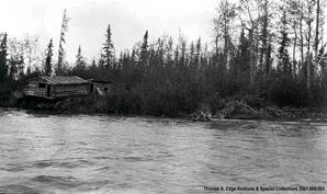 A shore line with two wooden structures. The structure look in need of repair, [Alberta].