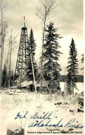 One oil drill tower in a field of snow, Fort McMurray. Note on the front reads: ""Oil Drill - Athabaska River"". Note on the back reads: ""Drilling for oil near McMurray by 1909 or 1910.