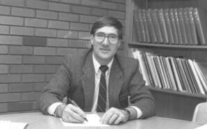 Dominque Abrioux seated at President's office boardroom table, Athabasca, Alberta