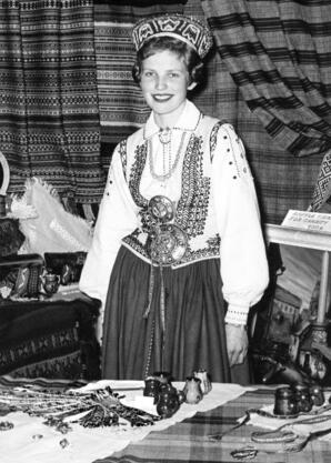 Girl in Latvian traditional dress with Cultural Artifacts table